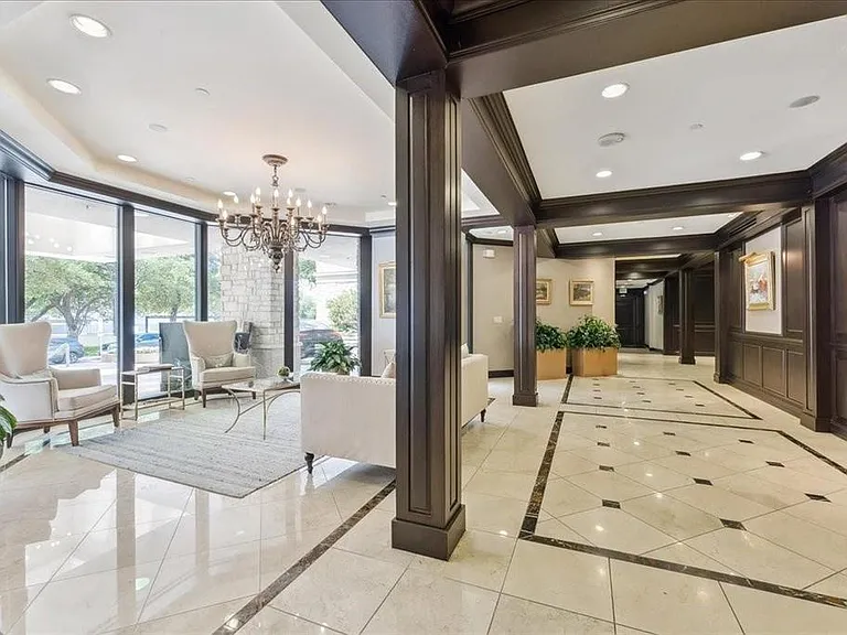 Spacious entry featuring polished tile flooring with dark accent borders, dark wood paneling and trim, recessed lighting, and a prominent chandelier
