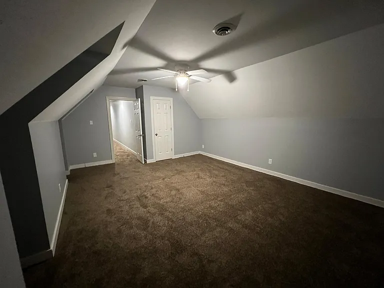 Bedroom 3 located above the garage with walk in closet door on the right and hallway to the left