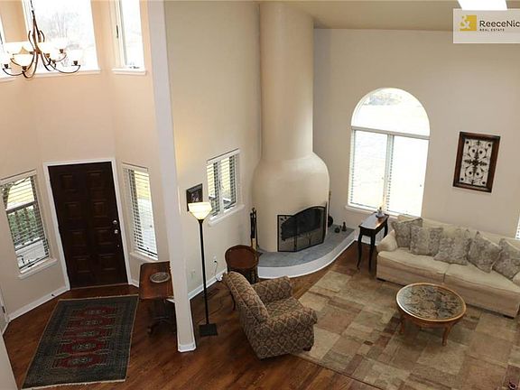 View from the soaring balcony, displays a roomy entry and featured wood burning adobe style fireplace surrounded by beautiful hardwood floors and lots of natural light!