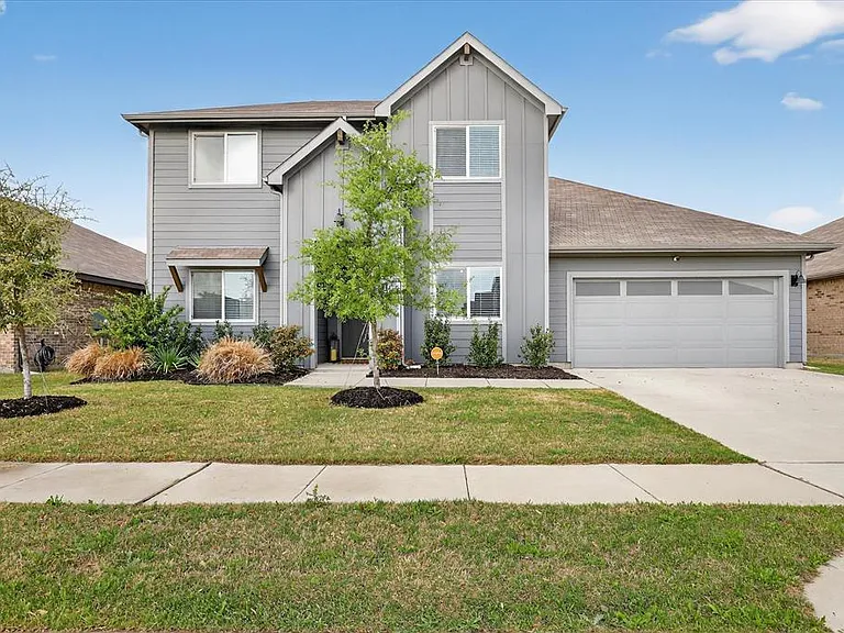 Contemporary two-story residence featuring a light gray exterior, an attached garage with panel windows, and a concrete driveway