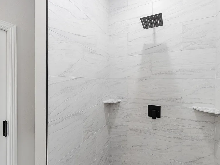 Spa like shower featuring a large walk-in rainfall shower head and shelving. Water heater is tankless allowing for exceptional hot water supply and water pressure. Tenant has a private washer/dryer.