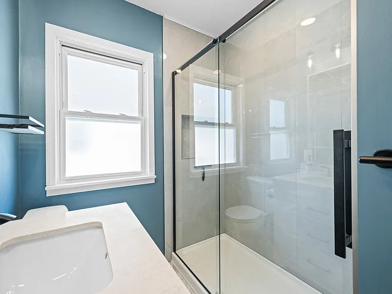 This is the updated bathroom on the second/main floor of the unit. It's located between the two bedrooms, and it includes a tile shower.
