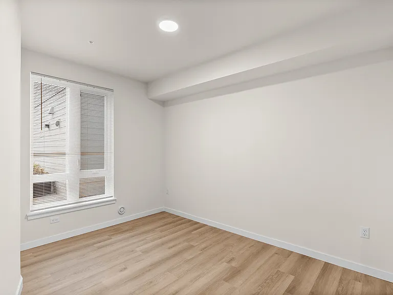 Bright, modern bedroom featuring warm wood-style flooring and a large window for natural light. Bright, modern bedroom featuring warm wood-style flooring and a large window for natural light.
