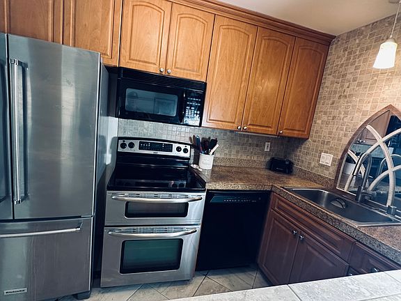 fully stocked kitchen with full size refrigerator, electric stove, microwave dishwasher and sink.