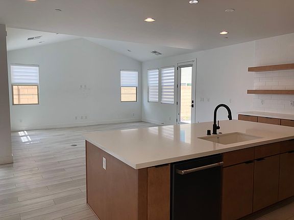 Kitchen looks out to an expansive great room with high ceilings. Right side of door leads you to the backyard.
