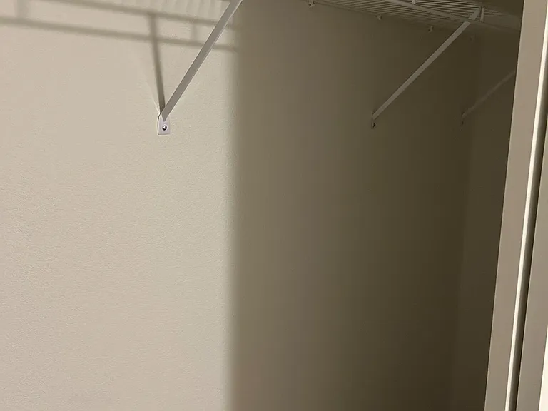 Dedicated closet with a sturdy wire shelf and hanging rod, offering practical storage for clothing and linens.