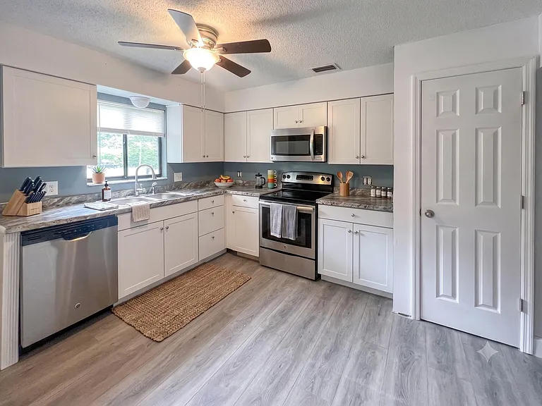 L-shaped kitchen with ample cabinet storage, stainless-steel appliances, and generous counters plus a window over the sink.