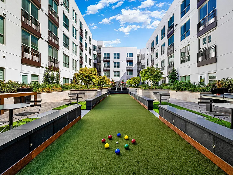Bocce ball court surrounded by greenery and modern buildings