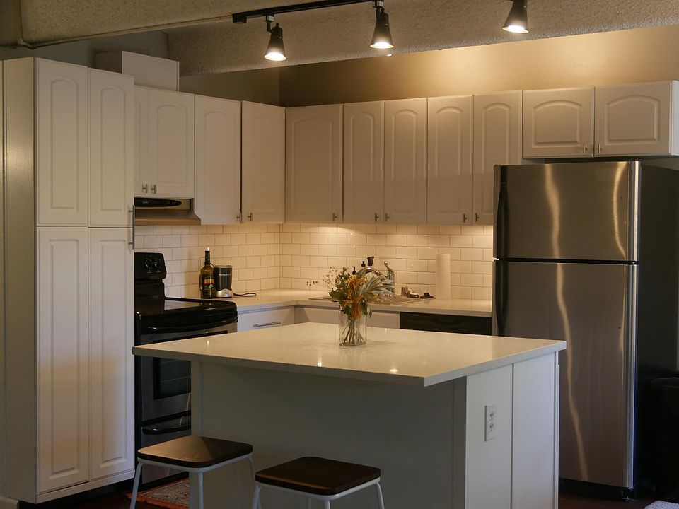 White kitchen with stainless steel appliances, quartz countertops and subway tile backsplash