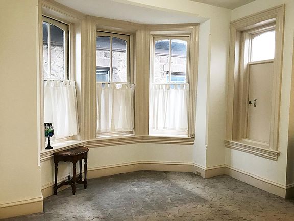 View of beautiful bedroom with gorgeous original wood moldings, Italianate round top windows and nine and one half foot ceilings.