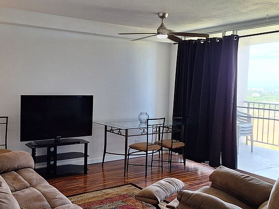 Wide angle of the living room from the entryway. Open feeling being able to experience the view from the lanai and a pass-through area into the kitchen.