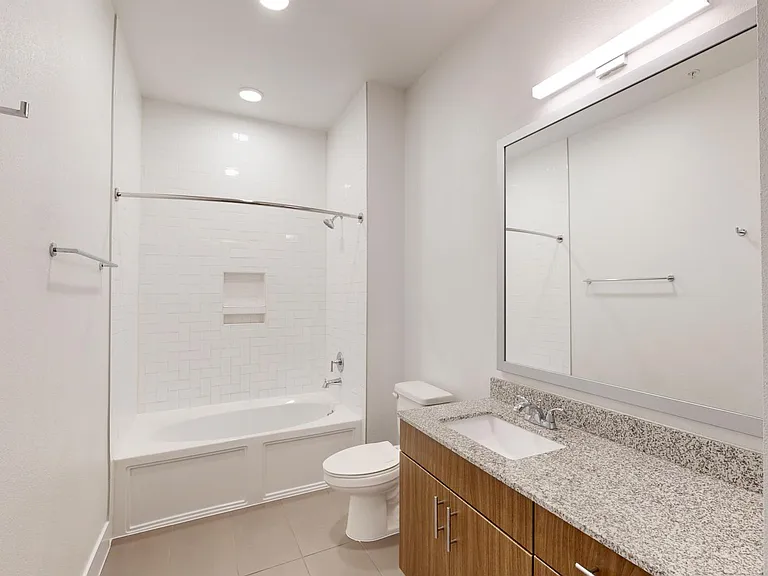Apartment bathroom with large soaking tub and tile flooring.