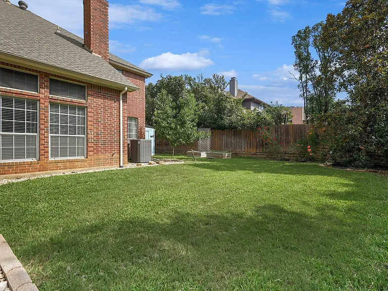 Expansive green lawn bordered by a block-paved edge and decorative stone