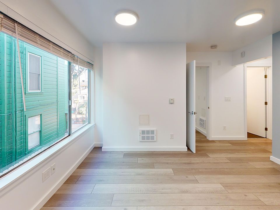 Spacious living room with wood-like flooring and a large window offering natural light