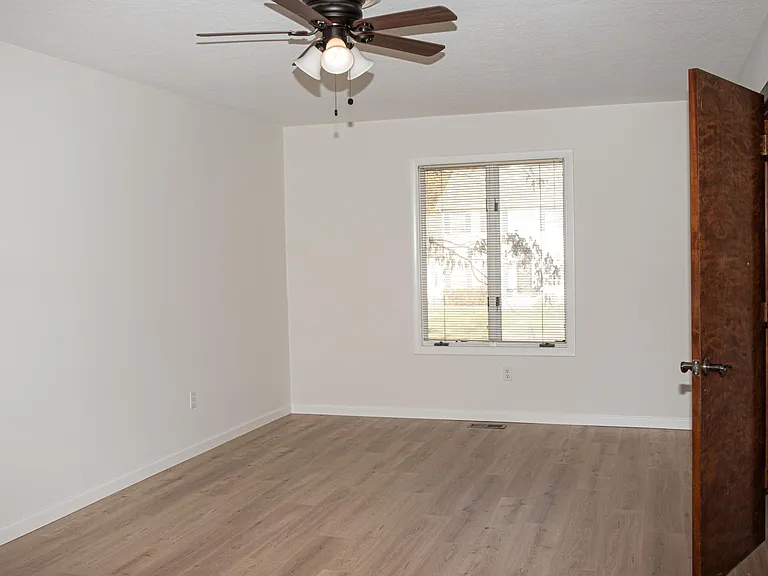 Large downstairs bedroom with ceiling fan and new flooring