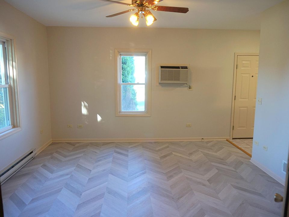 Spacious living room with new flooring, ceiling fan, and wall fit air conditioner.