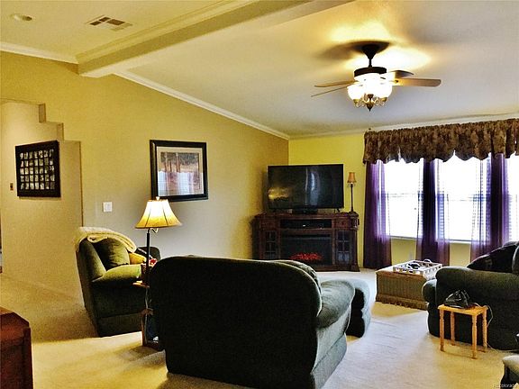 Living room has southern exposure, vaulted ceiling and ceiling fan with lighting