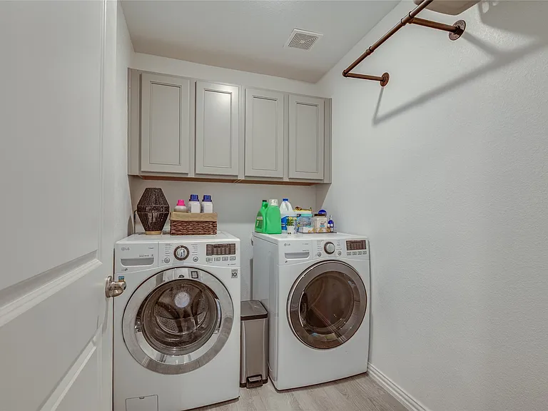 Dedicated laundry area featuring light gray shaker-style cabinetry, wood-finish flooring, and a wall-mounted metal hanging rod