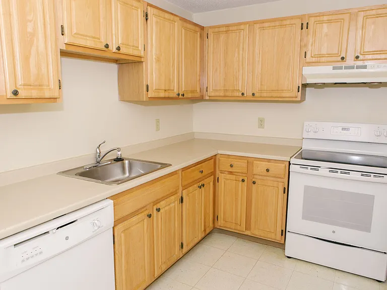 Kitchen With Oak Cabinets, White Appliances And Cream Laminate Counters.