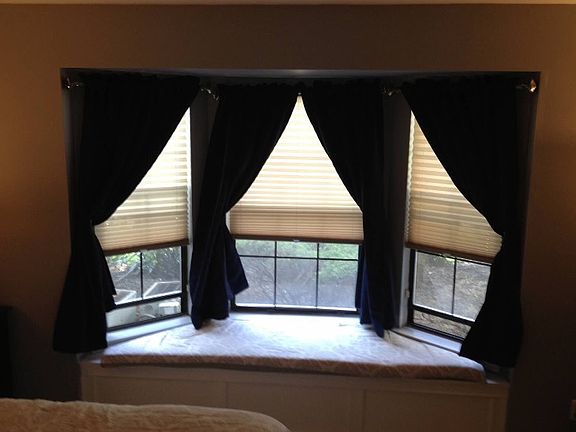 Large bay window in bedroom with storage and cushioned seat.