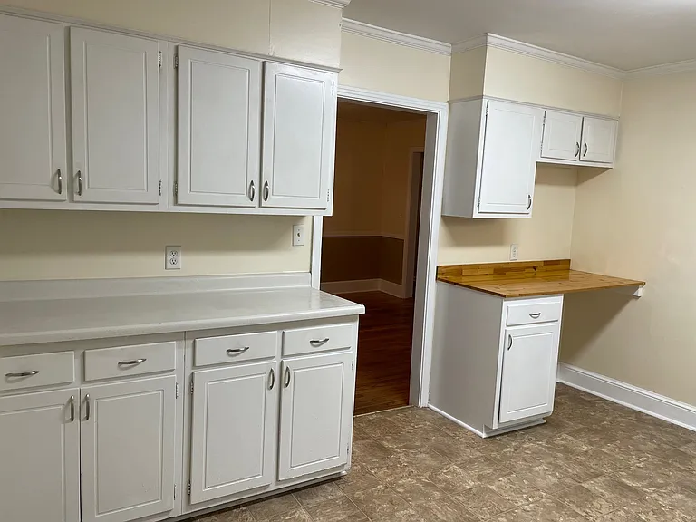 Lots of counter space, cabinets, and a desk in the kitchen. View into the dining room.