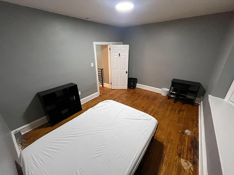 Private bedroom with wood-look flooring, neutral walls, and space for a full bed plus a small desk or dresser.