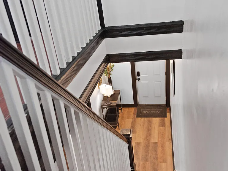Welcoming stairwell and entry landing with durable wood-look flooring, classic railings, and convenient space for a console t