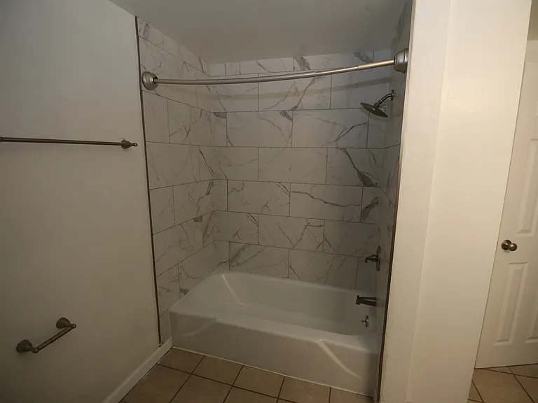 Elegant bathroom featuring a sleek marble-tiled shower and bathtub combination, offering a luxurious retreat.