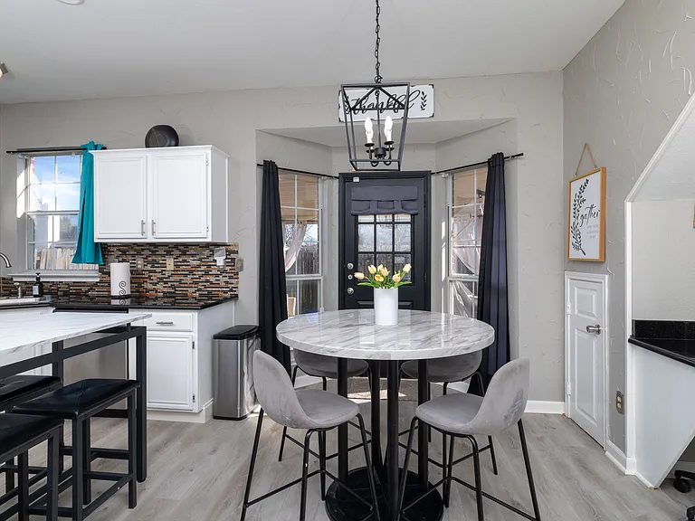 Stylish dining nook and modern kitchen with marble accents.