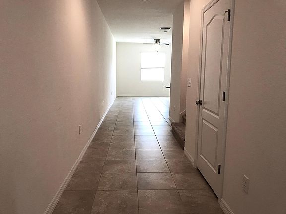 View from the entry way with a door to the garage to the right (not pictured), followed by a 1st floor bathroom, staircase and the living space and kitchen