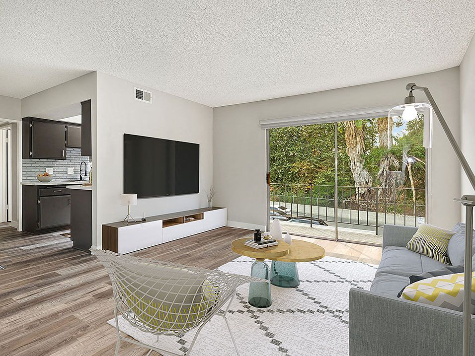 Hardwood floored living room with view of balcony and kitchen.