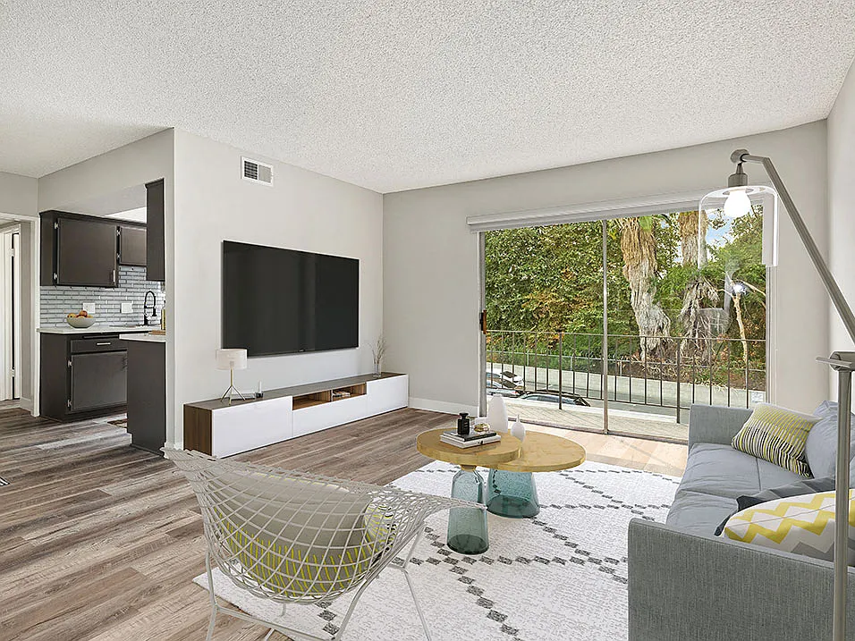 Hardwood floored living room with view of balcony and kitchen.