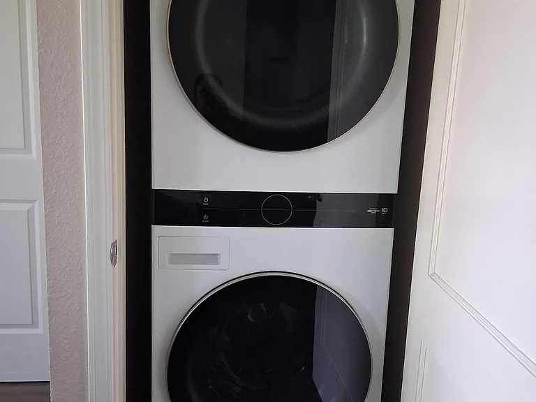 Convenient laundry closet with a stacked front-load washer and dryer for easy in-home laundry.