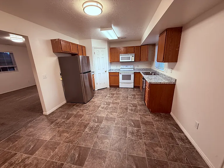 Kitchen and dining area, family room to left. There is space for a desk along the right wall, between the cabinet and the back door.