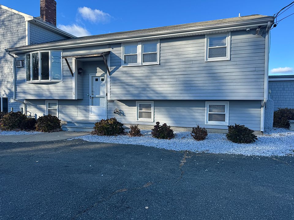 A well-maintained raised ranch_style building with updated siding, clean white-stone landscaping, and off-street paved parking. Private entrance for Apartment A is shown at the front.