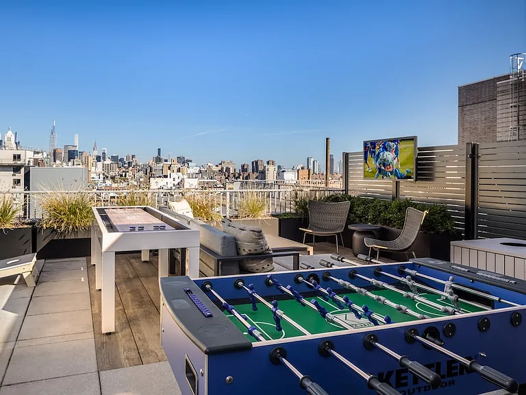 Rooftop terrace with lounge seating, foosball table, shuffleboard, and cornhole set