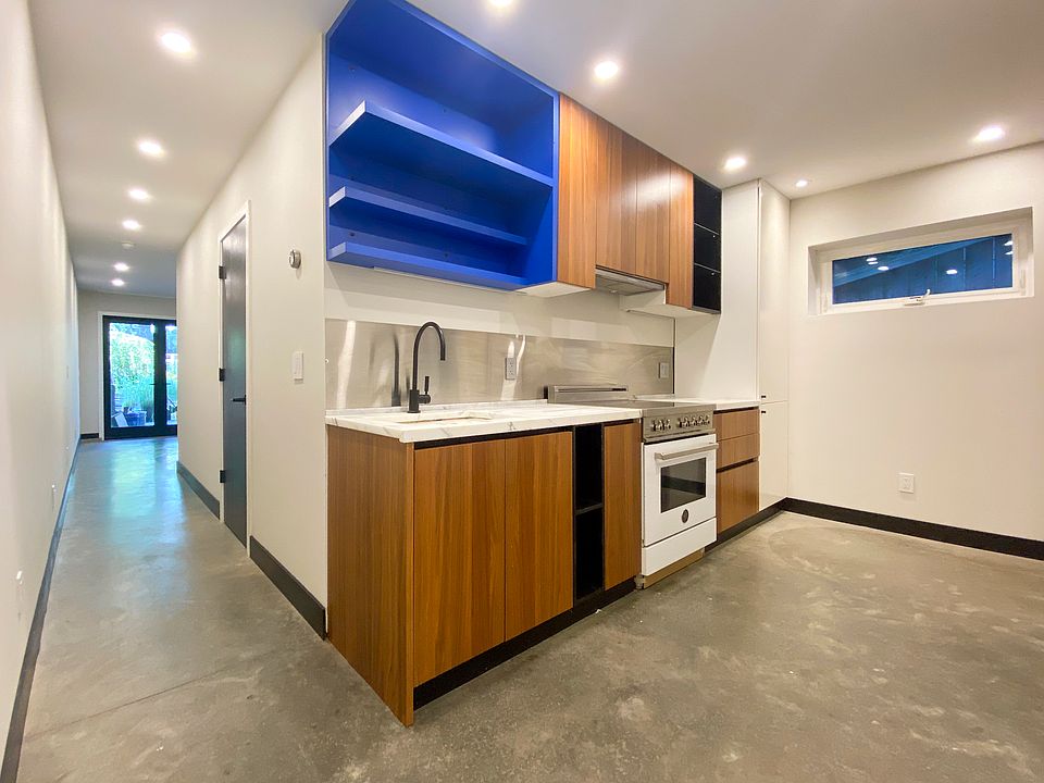 Kitchen with induction range, marble countertops, vented hood