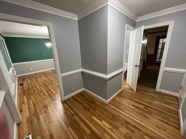 Entry way of home from front door, looking in front. To the left with the green wall paper is the dining room. Downstairs hall bathroom and family room straight ahead. Across from hall bath is a hall closet pictured on the right.