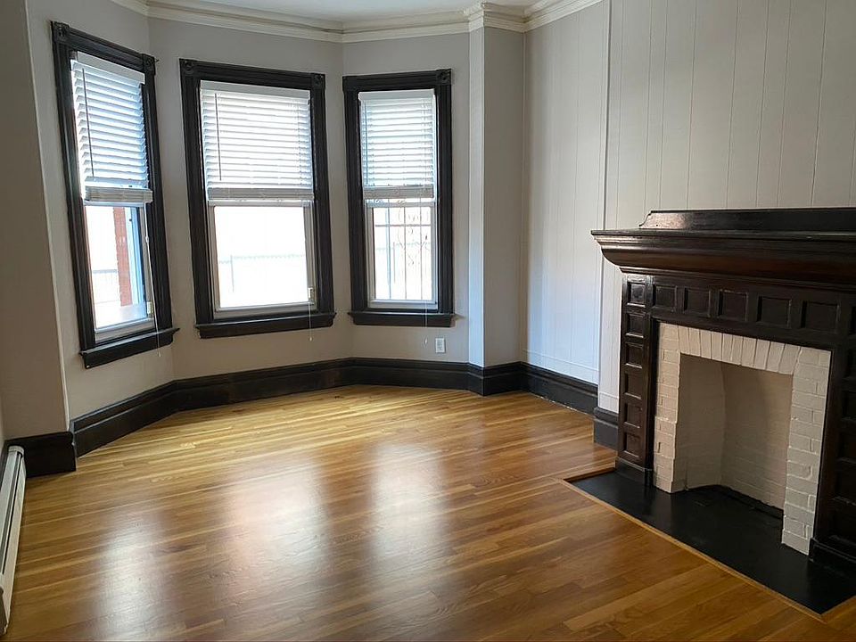 Sunny, spacious living room with hardwood floors and non-working fireplace.