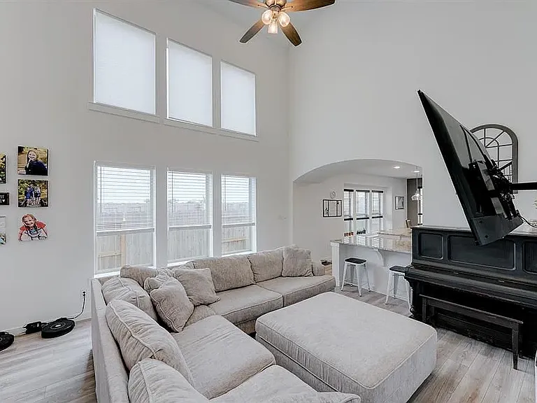 The spacious living room with HUGE windows that have roman shades on top and blinds on the bottom
