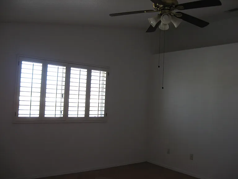 spacious master bedroom has plantation shutters and ceiling fan