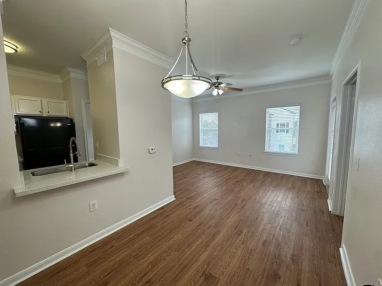 Bright and modern living space with wood-style floors, adjacent kitchen with granite countertops, and elegant lighting fixtures. Bright and modern living space with wood-style floors, adjacent kitchen with granite countertops, and elegant lighting fixture