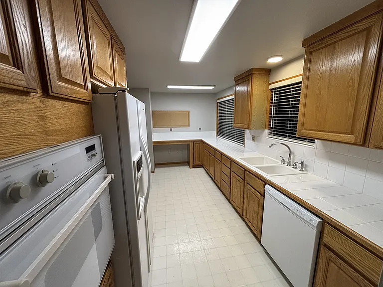 View of kitchen from the dining room. Note the built in Jenn Air wall oven, Jenn Air refrigerator, and brand new dishwasher