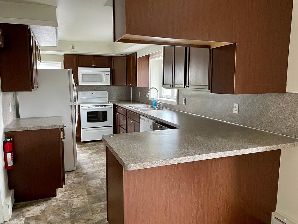 Kitchen with counter overhang for seating. Dishwasher, microwave, fridge, and electric range.