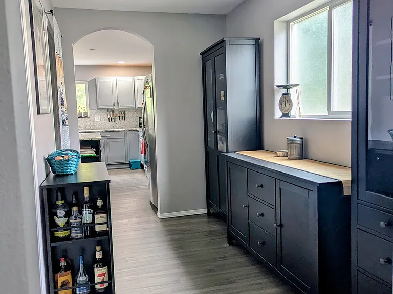 A view from the Office through the Butler's pantry to the kitchen. On the left is a bathroom and then the walk-in pantry. The furniture can remain or be removed as desired.
