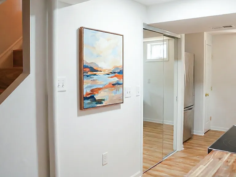 Hallway view showing the apartment's bright finishes, stair access, and open flow.