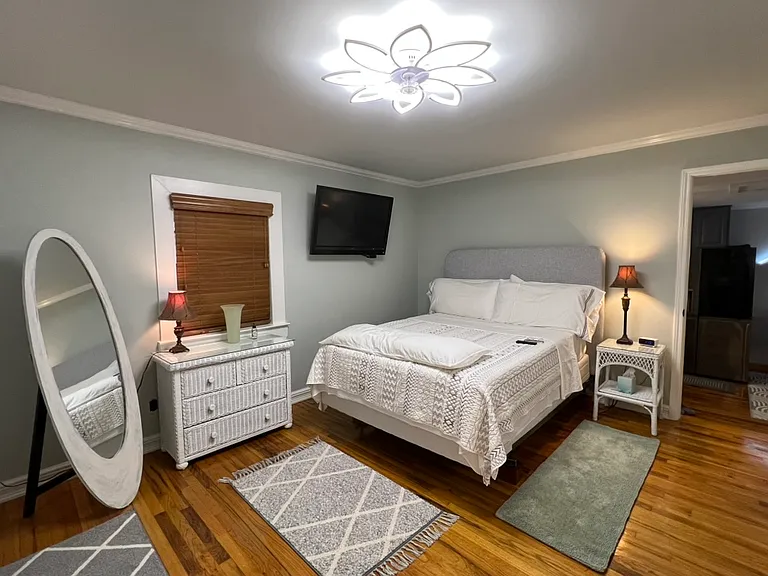 16x12 large bedroom. Queen bed with comfy topper. Loads of king pillows. Cushioned headboard. Full length mirror. Wall mounted 42 inch Vizio smart TV. Two dressers with lots of drawers. LED ceiling light with fan. Hardwood floors with rugs. Lamps.