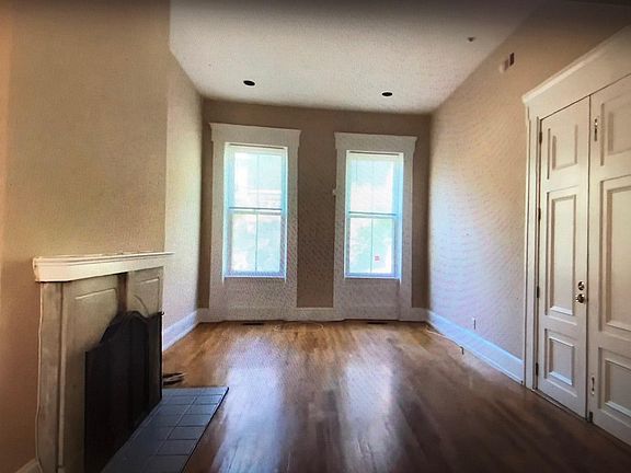 Living room with 12 foot ceilings, fireplace and southern exposure windows from kitchen