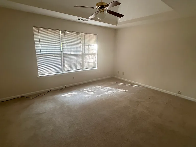 Primary bedroom on main level with trey ceiling and fan
