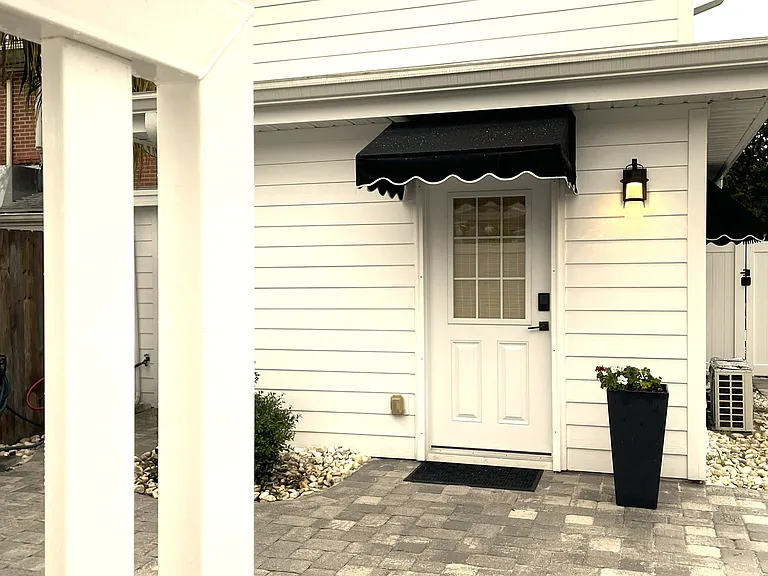 Pristine and private back patio area with elegant stone pavers and a secure white vinyl privacy gate. Offers a quiet, beautifully curated exterior space to relax in a peaceful neighborhood.
